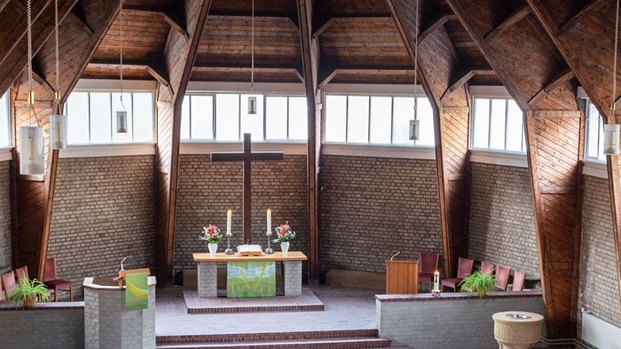 Ein moderner Wohnraum mit hohen Decken und großen Fenstern, eingerichtet mit Holz und grünen Akzenten.