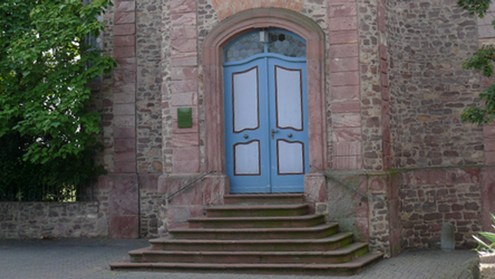 Historischer Ziegelsteingebäude-Eingang mit blauen Doppeltüren und steinernen Stufen.