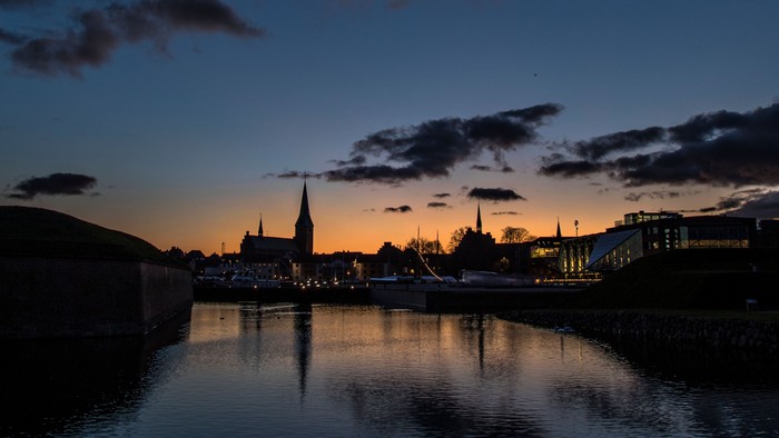 En by ved sundown med kirke og huse ved en sø