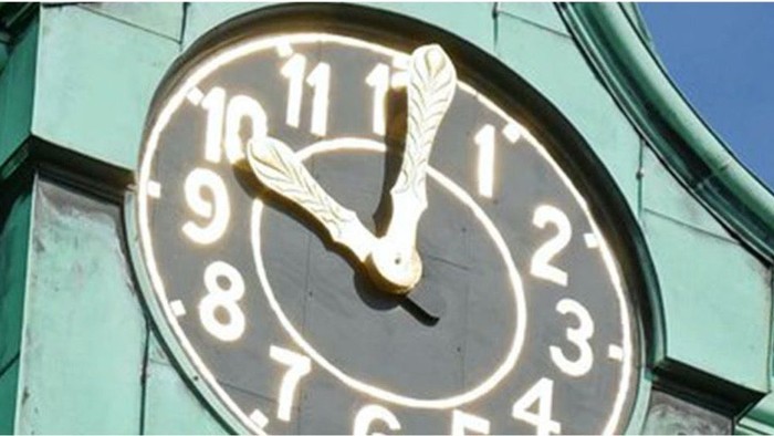 Das Bild zeigt eine große Uhr an einem grünen Turm.