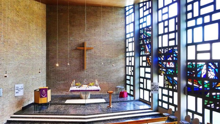 Moderne Kircheninnenraum mit Buntglasfenstern und hölzernem Kreuz