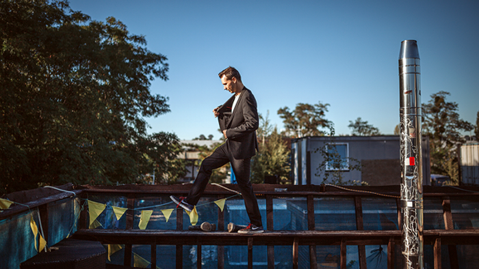 Ein Mann im Anzug schreitet selbstbewusst über eine hohe, schmale Brücke während der goldenen Stunde.
