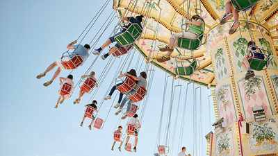 Bunter Schaukelkarussell mit Fahrgästen, die eine fröhliche, kopfüber Fahrt unter strahlendem Himmel genießen.