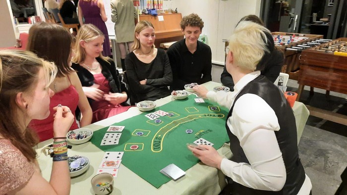 Eine Gruppe von Menschen spielt Poker um einen grünen Tisch.