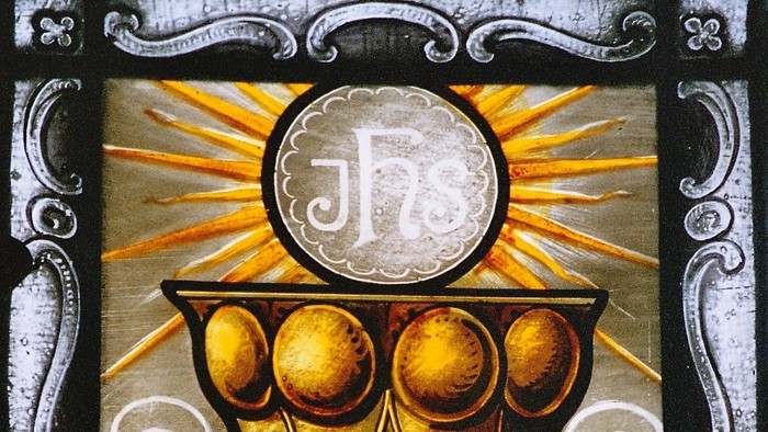 Das Bild zeigt einen goldenen Kelch mit Strahlen und Symbolen.