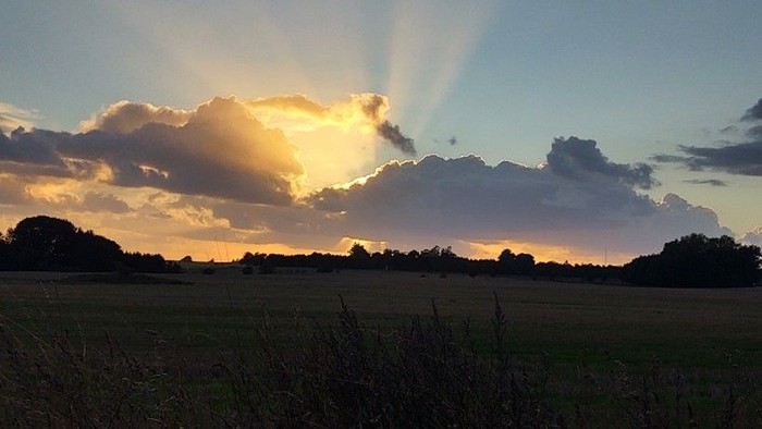 En skøn solnedgang over et åbent landskab med skyer.