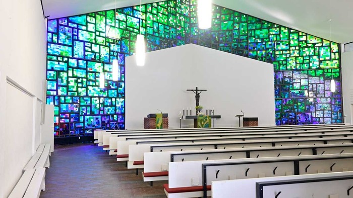 Die Kirche hat bunte Glasfenster und weiße Bänke