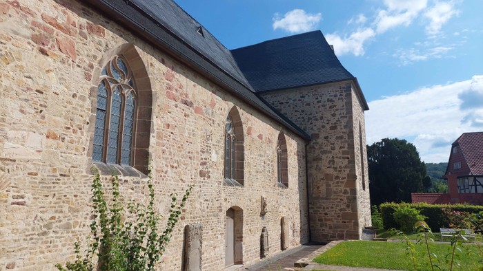 Alte Steinkirche mit Rundbogenfenstern und grünem Rasen.