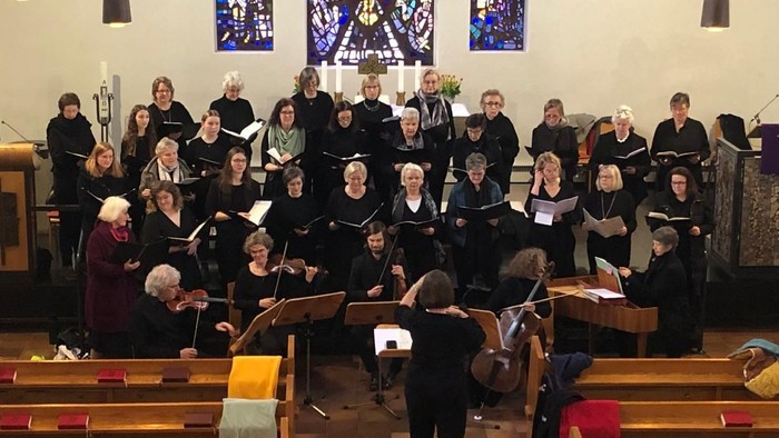 Ein Chor singt in einer Kirche, begleitet von einem Orchester.