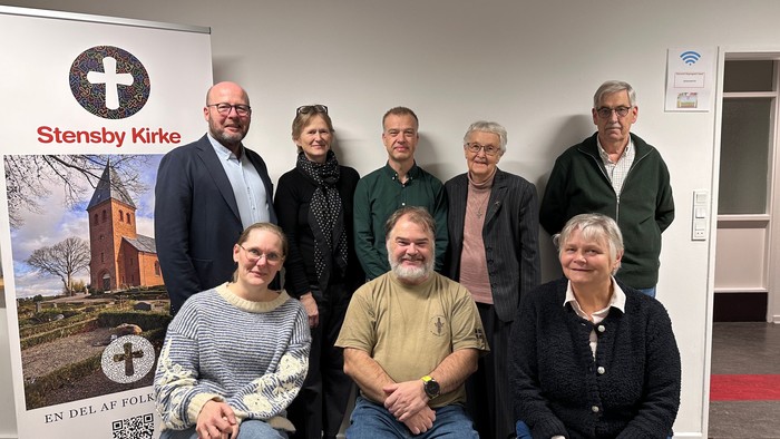 Gruppe af mennesker, der poser sammen foran et banner