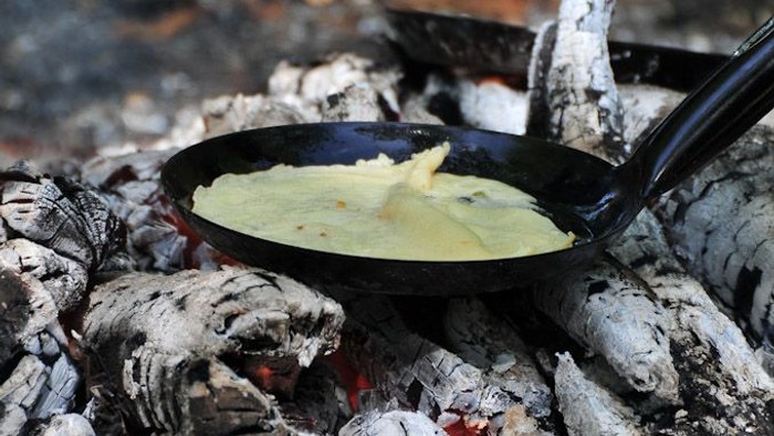 En kage koges i en pande over en åben ild.