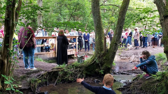 Taufszene an einem Bach im Wald