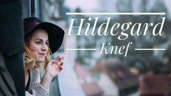 Eine Frau mit Hut schaut aus einem Fenster, darüber liegt der Text *„Hildegard Knef“*.