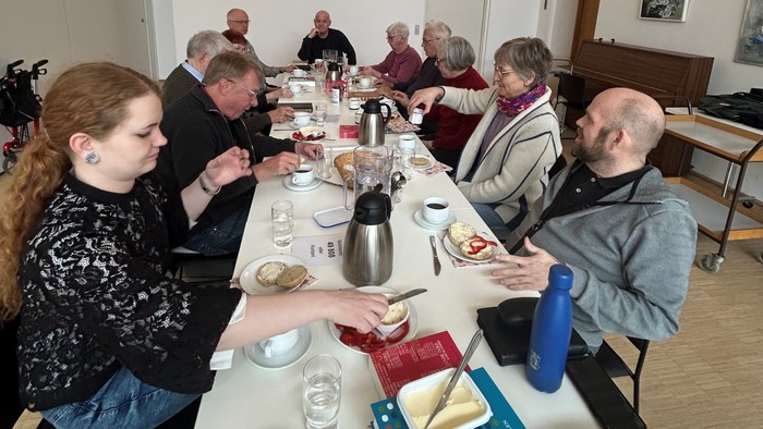 En gruppe af mennesker sidder ved et langt bord og spiser.
