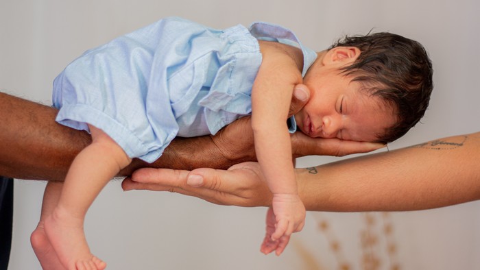 Sovende baby på fars arm.