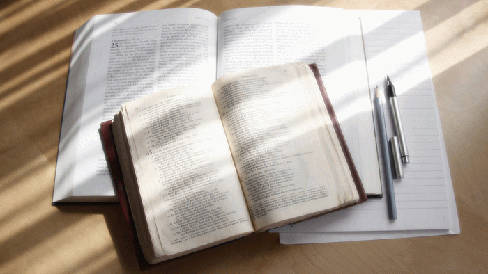 Offene Bücher und ein Notizblock auf einem Holztisch