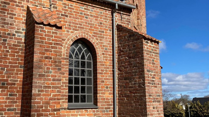 Røde murstensbygning med spidsbuefænster og tårn.