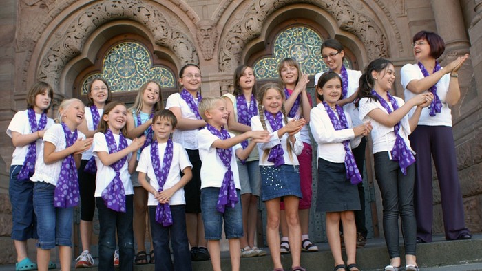 Gruppe von Menschen mit Lila-Bändern vor Gebäude