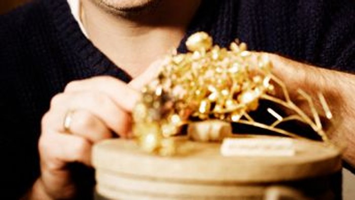 En glad mand holder en træskål fyldt med gyldent, revet kokos og en ske.