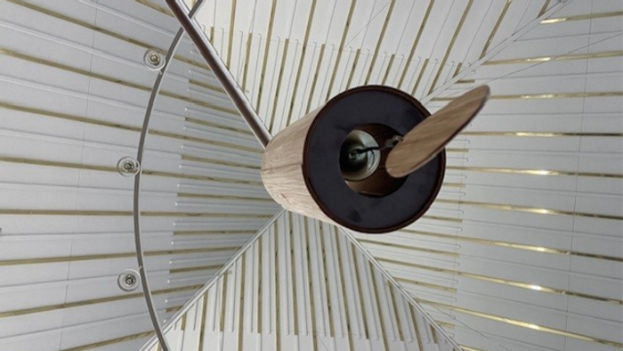 En moderne ventil med treblade hænger fra et hvide tagesystem.