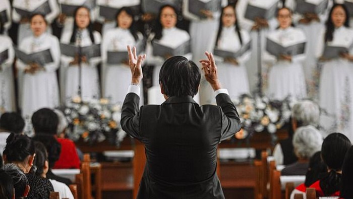 En korleder dirigerer et stort kor i kirke.