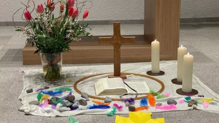 Ein Altar mit Kreuz, Kerzen, Blumen und bunten Papierschnipseln