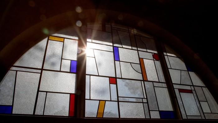 Buntes Kirchenfenster mit geometrischen Mustern und Sonnenlicht