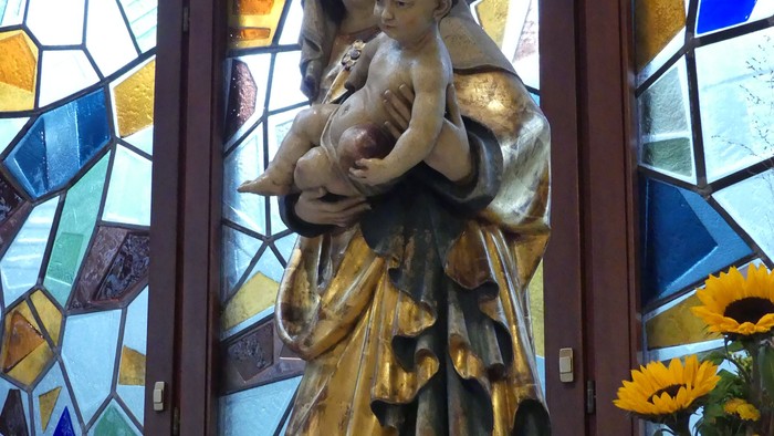 Heilige Muttergottes Statue vor buntem Kirchenfenster