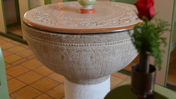 En smukk, hvid keramisk fontæne med udsmykning og en blomst i den.