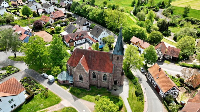 Dorf mit Kirche und umgebender Landschaft
