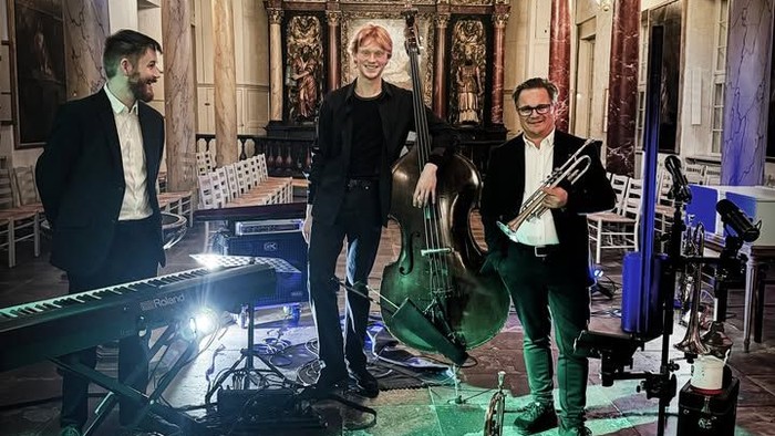 Et live jazzkvartet optræder i en elegant oplyst, historisk indendørs lokation med grønt lys på gulvet.