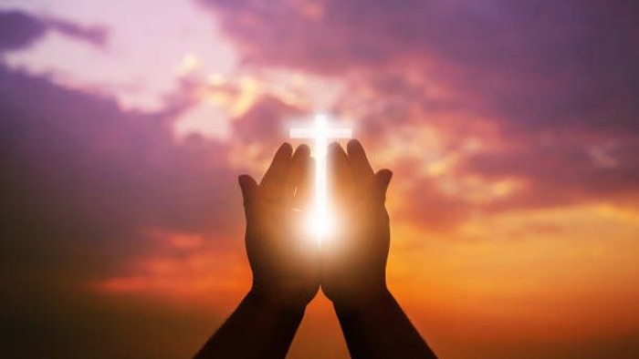 Hände halten strahlende Sonne vor Sonnenuntergang