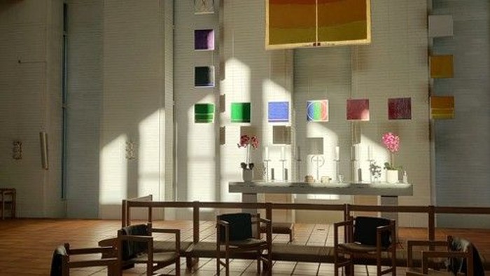 Kirkeinteriør med farvede glasvinduer og kirkebænke