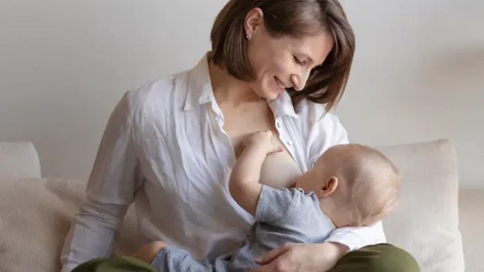 Eine Frau stillt ihr Baby, während sie auf einem Sofa sitzt.