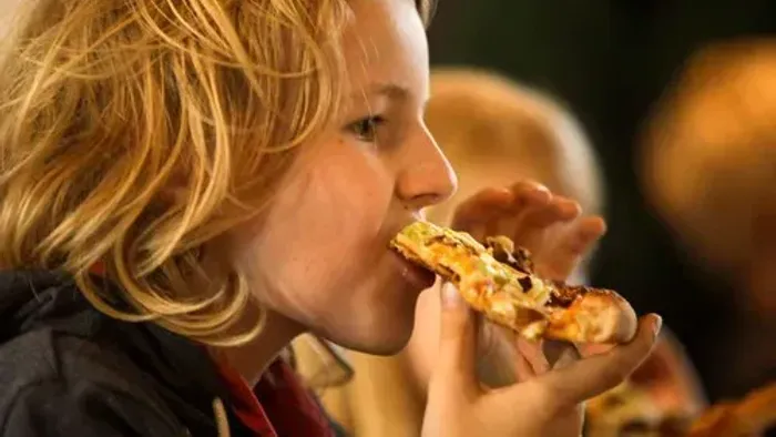 Et barn spiser en pizzering.