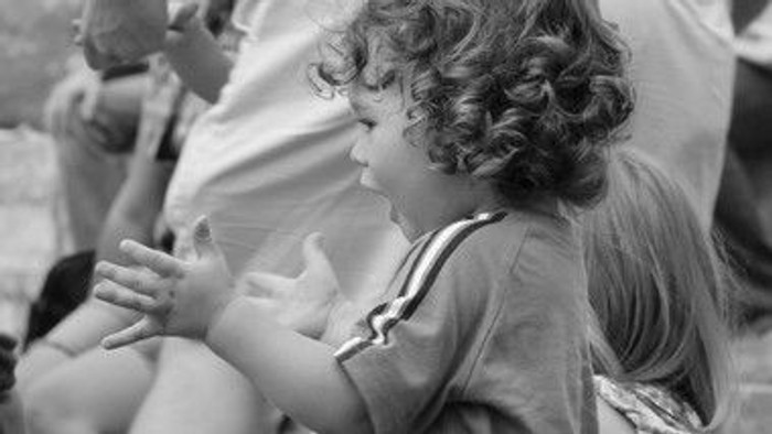 To børn sidder tæt på hinanden, et af dem holder en lille genstand.