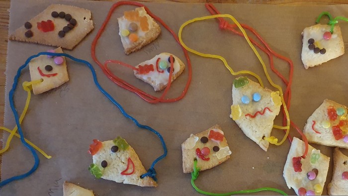 Bunte Kekskäse-Mäuse mit Süßigkeiten-Dekoration auf Backpapier.