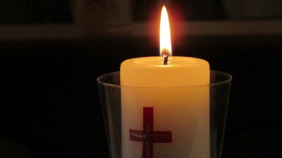 Zwei brennende Kerzen mit Kreuzsymbolen in Glasbehältern