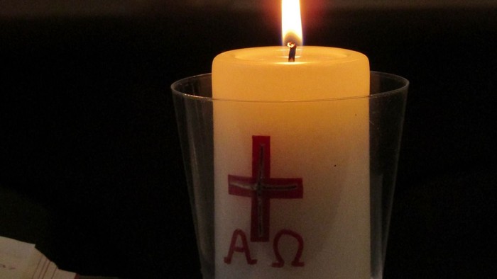 Zwei brennende Kerzen mit Kreuzsymbolen in Glasbehältern