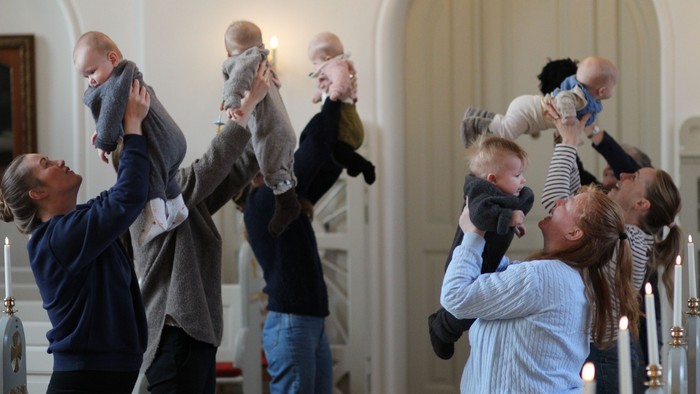 En gruppe voksne holder børn oppe i luften i et rum