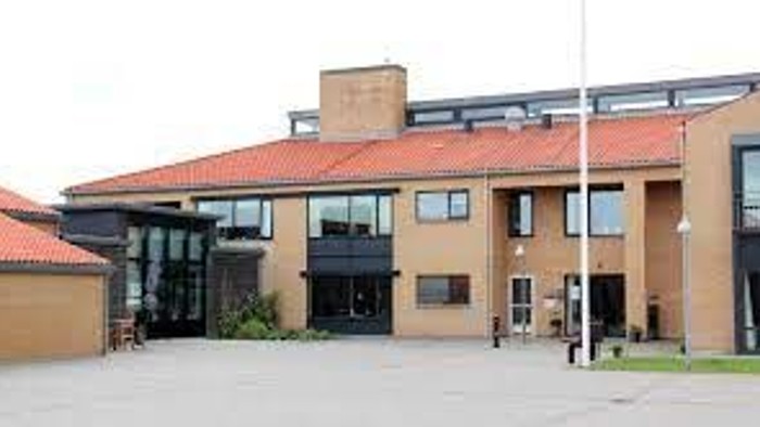 Et moderne hus med store vinduer og røde tag.