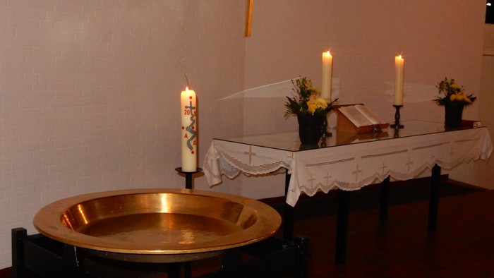 Ein goldener Taufbecken, Kerzen und Blumen in einer Kirche