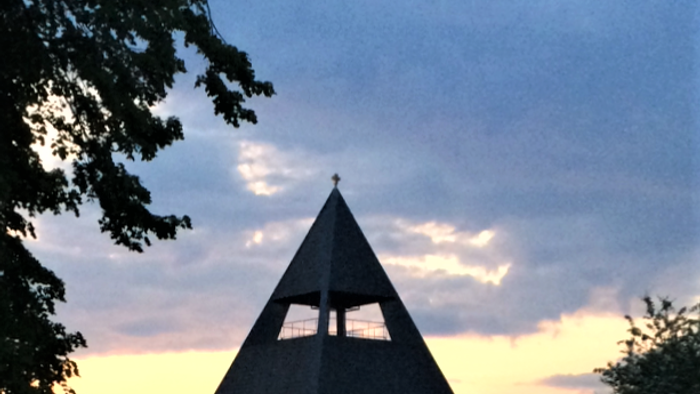 En pyramideformet kirke med tårn og en rød murvej til.