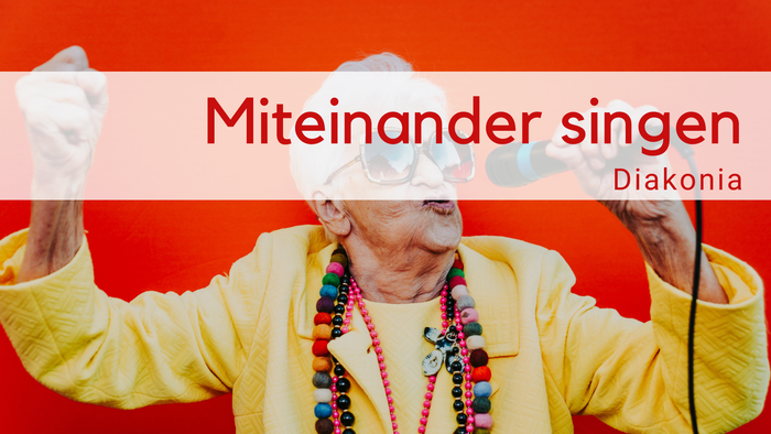 Weißhaarige alte Frau mit cooler Brille, gelbem Oberteil, bunten Ketten singt mit Mirkofon auf rotem HIntergrund