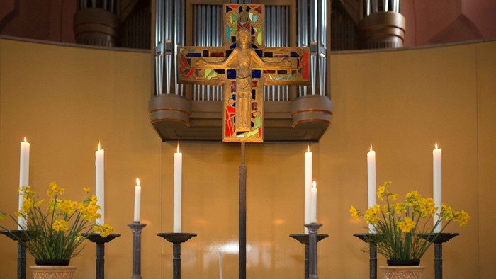 Kirchenaltar mit Kerzen, Blumen und einem aufgeschlagenen Buch