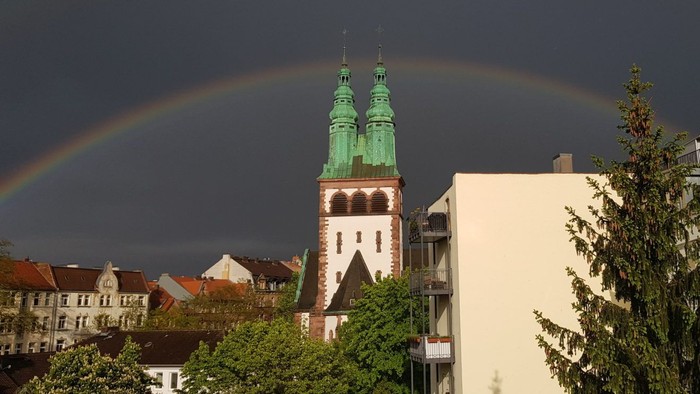 Regenbogen über einer Stadt mit hohen Kirchtürmen.
