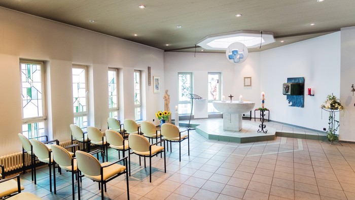 Ein moderner Kirchenraum mit weißen Stühlen und einem Altar