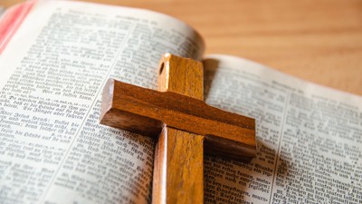 Ein hölzernes Kreuz liegt auf einer geöffneten Bibel