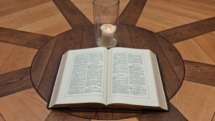 Offenes Buch und brennende Kerze auf Holztisch