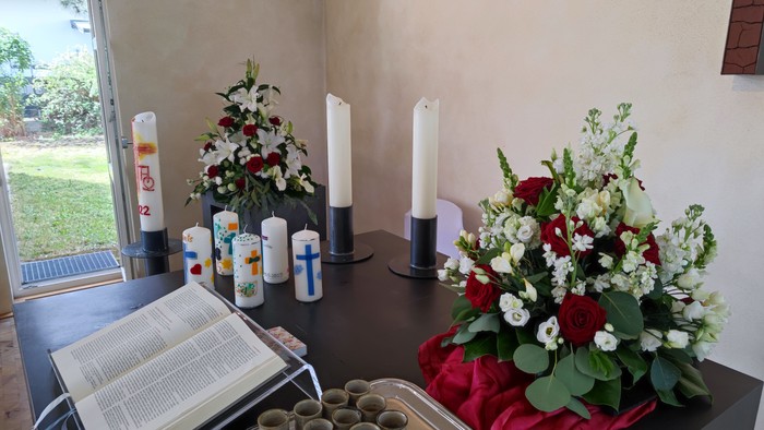 Traueraufbau mit offener Bibel, Kerzen, Blumenschmuck und Gedenkkerzen auf einem Tisch.